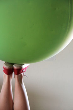 Ein Kind balanciert mit den Füssen einen Gymnastikball